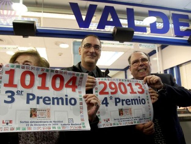 Los propietarios de la administraci&oacute;n de loter&iacute;a Vald&eacute;s, en Barcelona, muestran los carteles con los n&uacute;meros 10.104, tercer premio, y 29.013, cuarto. / EFE