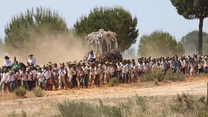 El Simpecado de la Hermandad de Huelva camina rodeado de peregrinos hacia la aldea para reunirse con la Blanca Paloma.