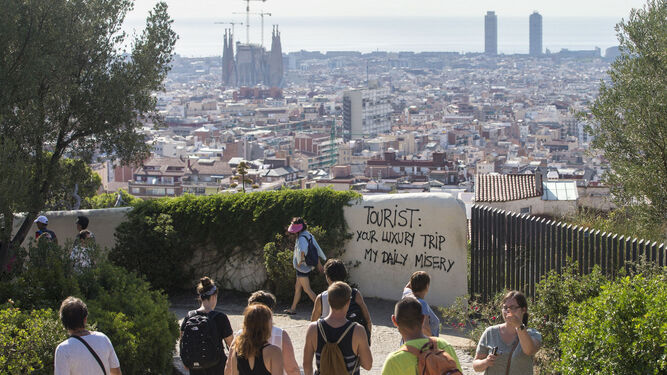 Un grupo pasea ante una pintada contra el turismo en Barcelona.