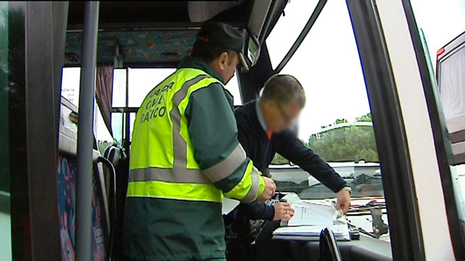 Un guardia civil realiza un control de tráfico al conductor de un autobús.