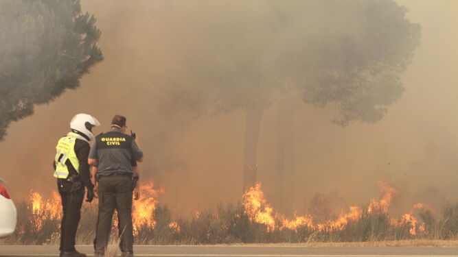 Dos guardias civiles frente a las llamas del incendio de Moguer.