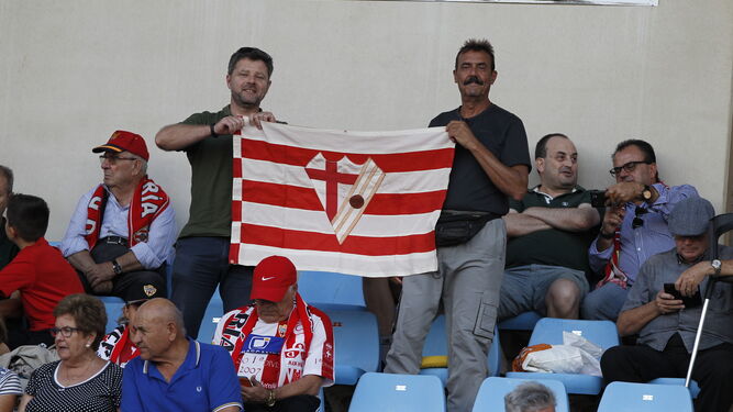Dos aficionados con una bandera de la AD Almería en el Mediterráneo.