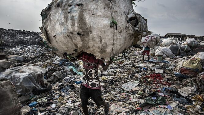 La imagen captada por el fot&oacute;grafo Kadir van Lohuizen, ganador del 1er premio de la categor&iacute;a 'Environment - Stories'. Se ve a  un hombre mientras carga un enorme lomo de botellas recogidas para su reciclaje en el vertedero de Olusosun en Lagos, Nigeria, el 21 de enero de 2017