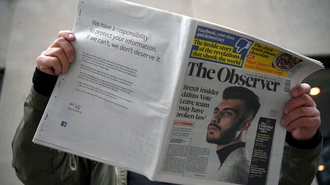 Un lector sostiene el ejemplar del 25 de marzo de 'The Observer' que incluyó la publicidad de Facebook en su contraportada.