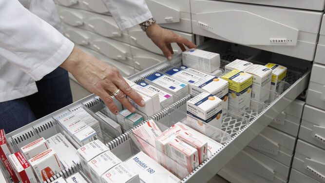 Un farmacéutico abre un cajón de medicamentos de su botica.