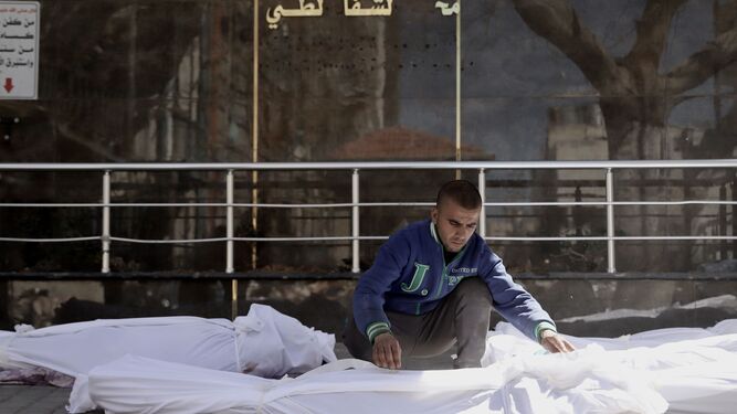 Un palestino coloca varios cadáveres en el Hospital Al Shifa, en la ciudad de Gaza.