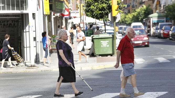 Una mujer mayor  espera para cruzar una calle.