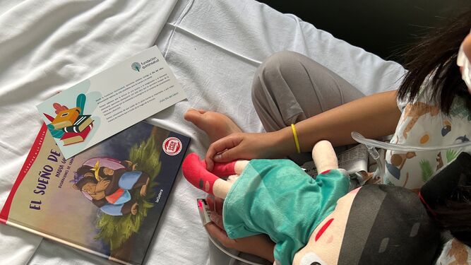 Una niña ingresada lee su libro, obsequio del hospital Quirónsalud para fomentar la lectura.