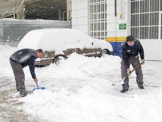 Unos hombres retiran la nieve acumulada ante las puertas de su negocio en la ciudad de Teruel.

Foto: Efe