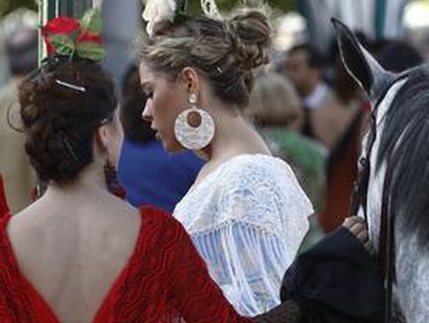 Dos chicas vestidas de flamenca junto a un caballo.

Foto: B.Vargas
