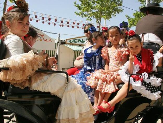Varias peque&ntilde;as vestidas de flamenca y montadas en un coche de caballos. 

Foto: Andres Mora