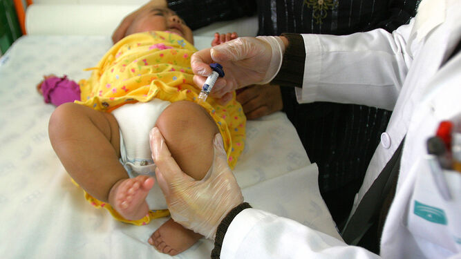 Una pediatra pone una vacuna a una niña en una consulta.
