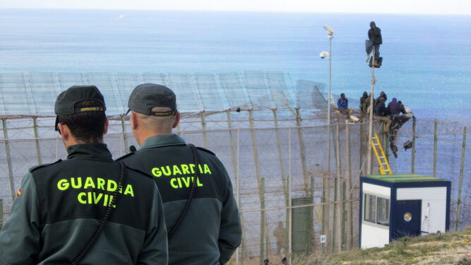 Dos agentes de la Guardia Civil observan cómo saltan la valla de Melilla varios subsaharianos en abril de 2014.