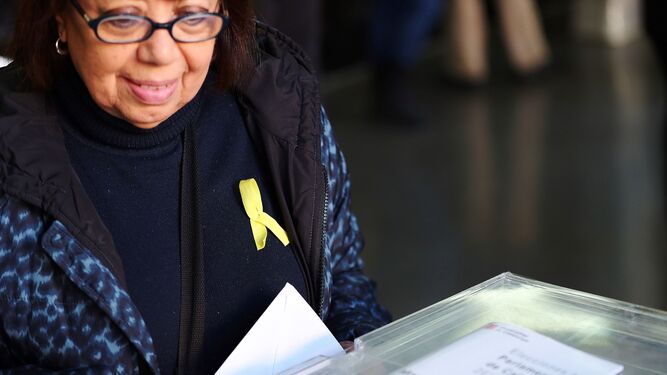 Una mujer vota con el lazo amarillo en su jersey