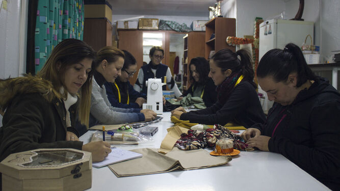Las mujeres alrededor de la mesa de trabajo del taller costura.