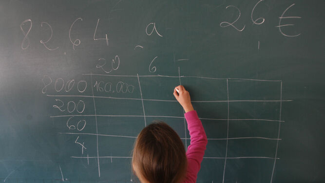 Una alumna realiza una operación de cálculo en la pizarra de su clase.