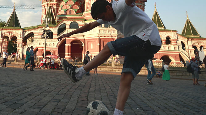Un niño juega con un balón de fútbol ante la Catedral de San Basilio en la Plaza Roja de Moscú.