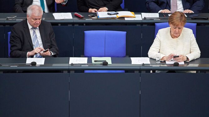 El ministro de Interior alemán, Horst Seehofer, y la canciller alemana, Angela Merkel, revisan ayer sus móviles en el Parlamento alemán.
