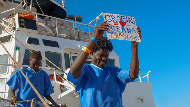 Un inmigrante muestra una pancarta de agradecimiento a España al desembarcar del 'Open Arms' en Algeciras