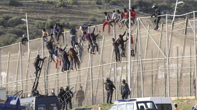 Inmigrantes encaramados en la valla fronteriza entre Melilla y Marruecos en octubre de 2014.
