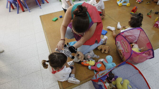Una docente juega con una pequeña de tres años que acaba de llegar a clase por primera vez.