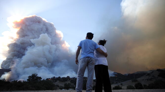 Dos ciudadanos observan el humo que desprende el incendio Woolsey en Malibú.