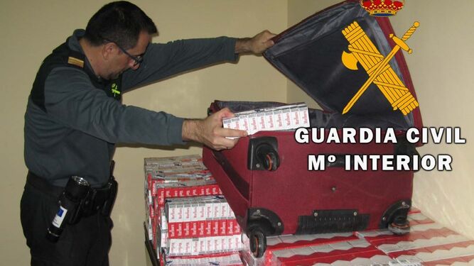 Un agente de la Guardia Civil inspecciona el tabaco ilegal aprehendido en el puerto