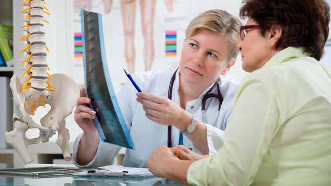 Una traumatóloga enseña una radiografía a una paciente.