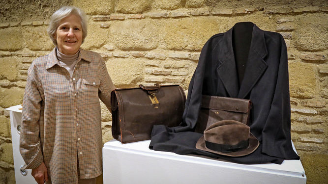 Carmen Negrín junto a la maleta, el gabán y el sombrero de su abuelo, que se exponen en la sala El Molino de El Alcázar de Jerez