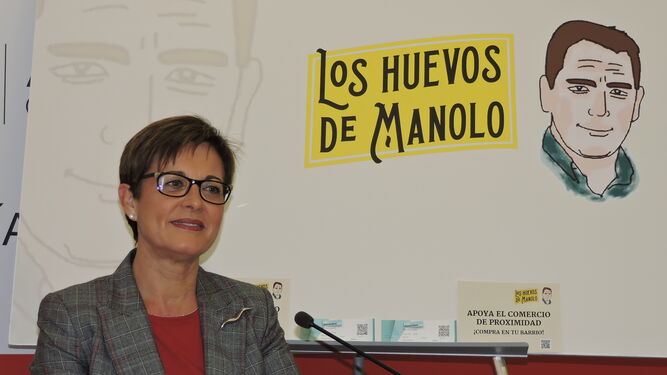 Adriana Valverde junto al cartel de la campaña de apoyo al comercio de proximidad