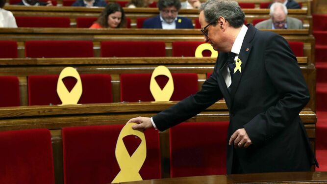 El presidente de la Generalitat, Quim Torra, coloca un lazo amarillo en un pleno del Parlamento catalán.