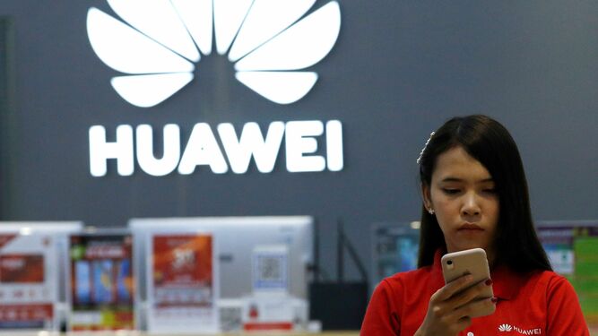 Una empleada revisa un teléfono Huawei en una tienda de Tailandia.