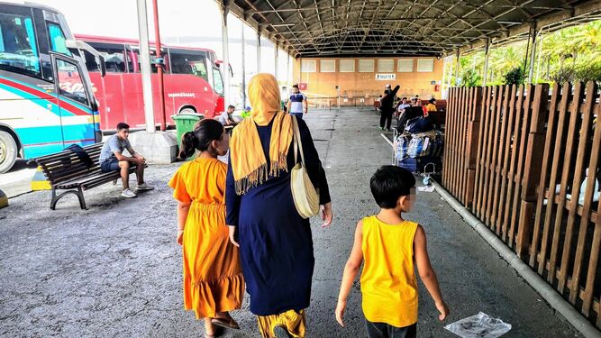 Una madre y sus dos hijos esperan la salida del autobús que les llevará a su lugar de residencia.