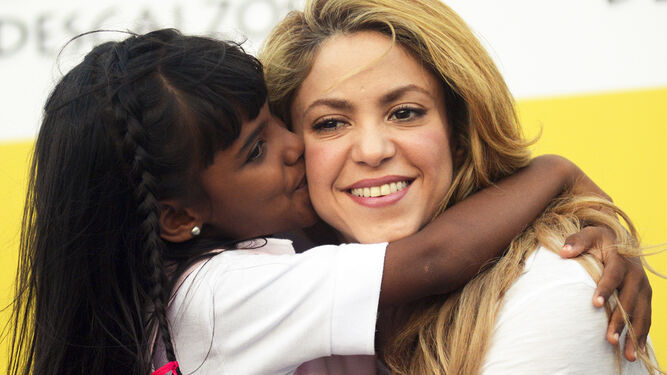 Shakira recibe el beso de una niña de Barranquilla, el pueblo colombiano en el que nació y que ayuda económicamente.