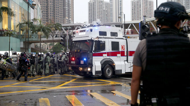 La policía antidisturbios se concentra junto a uno de los veículos equipados con caños de agua.