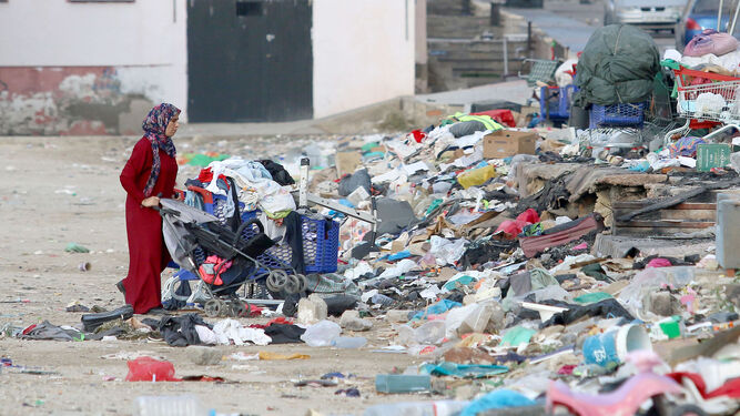 Una mujer atraviesa por el descampado de basura tras dejar a su hijo en la guardería