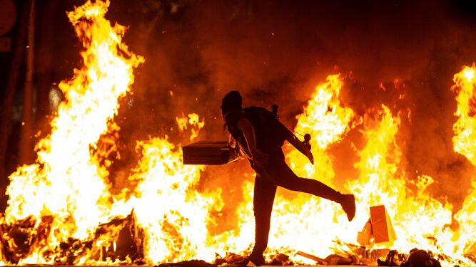 Uno de los manifestantes lanza objetos a una hoguera en Barcelona