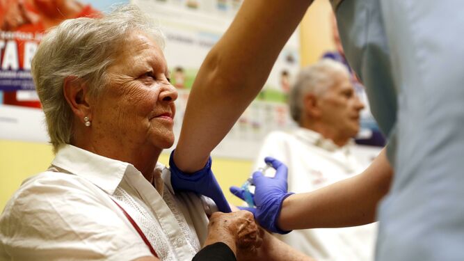 Una enfermera suministra la vacuna contra la gripe a una mujer mayor de 65, una paciente dentro del grupo de riesgo
