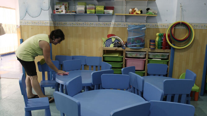 La trabajadora de una guardería prepara el mobiliario para los alumnos.