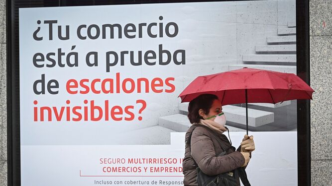 Una mujer pasea por delante de un anuncio del Santander.
