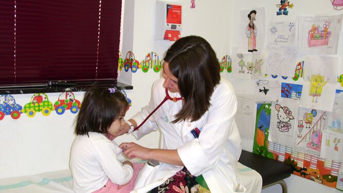 Una pediatra examina a una niña en su consulta.