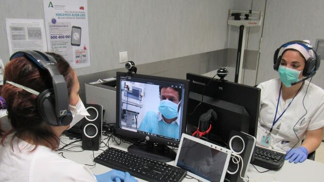 Dos sanitarias atienden a un paciente que recibe instrucciones por videoconferencia desde una cabina aislada