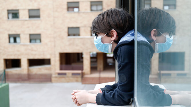 Un niño con una mascarilla se asoma a la ventana de su casa en Valdemoro (Madrid).