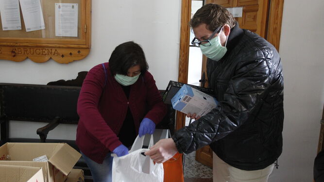 Ismael Gil ayuda a una voluntaria a cargar bolsas de guantes, mascarillas y geles.