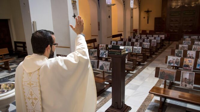 El párroco de Regiones, Antonio Salvador, celebra la misa con los retratos de sus feligreses.
