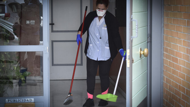 Una mujer limpia la puerta de una vivienda.
