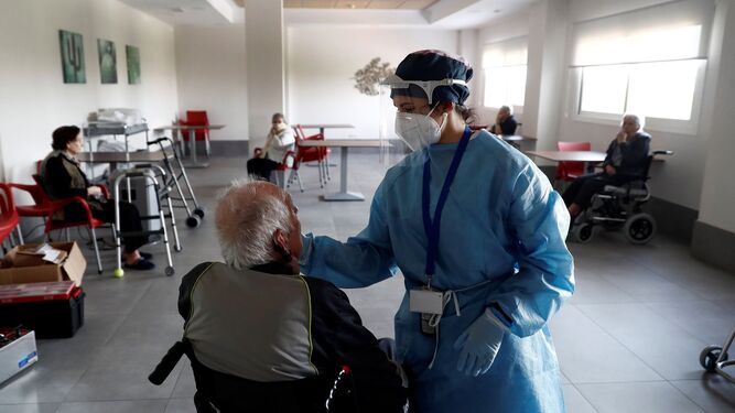 Un anciano atendido por una enfermera en una residencia.