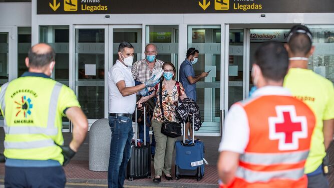 Dos viajeros reciben las indicaciones de los servicios de emergencias tras desembarcar este sábado en Lanzarote de un vuelo procedente de Madrid en el que parte del pasaje ha sido sometido a aislamiento después de que uno de los ocupantes del avión diera positivo en Covid-19.