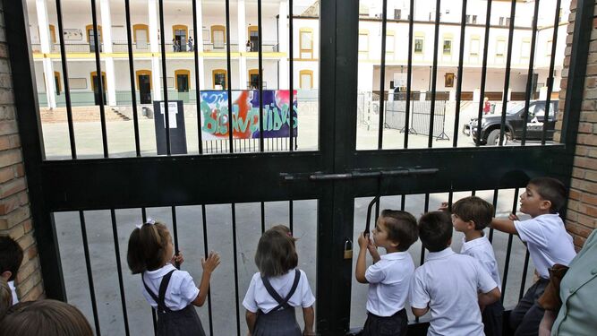 Alumnos de un colegio concertado se asoman a la puerta del recreo.