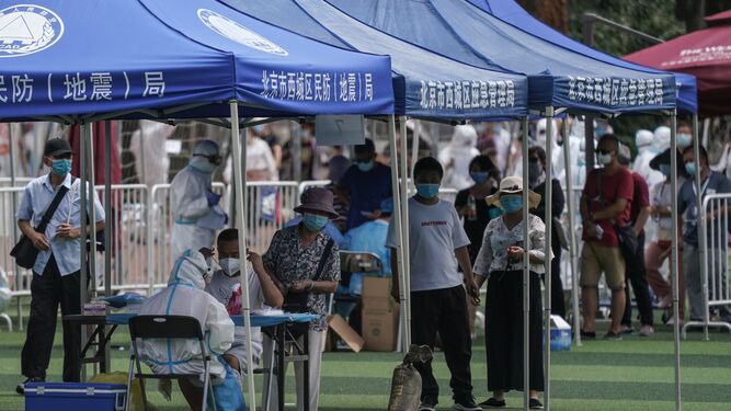 Personas que visitaron el mercado de Xinfadi hacen cola para hacerse el test de coronavirus en el pabellón deportivo de Guang'an en Pekín, China.
